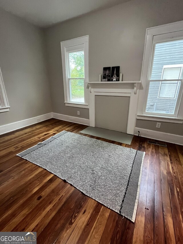 unfurnished living room with visible vents, baseboards, and dark wood-type flooring