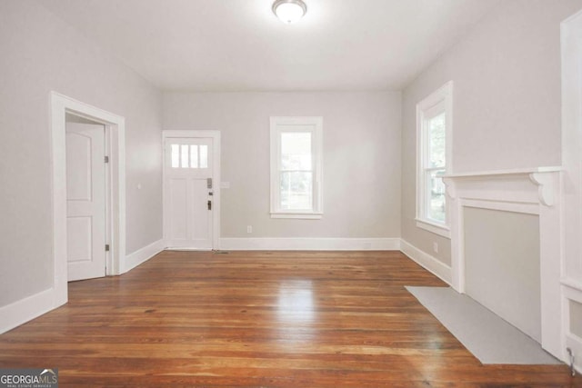 unfurnished living room with a healthy amount of sunlight and dark hardwood / wood-style floors