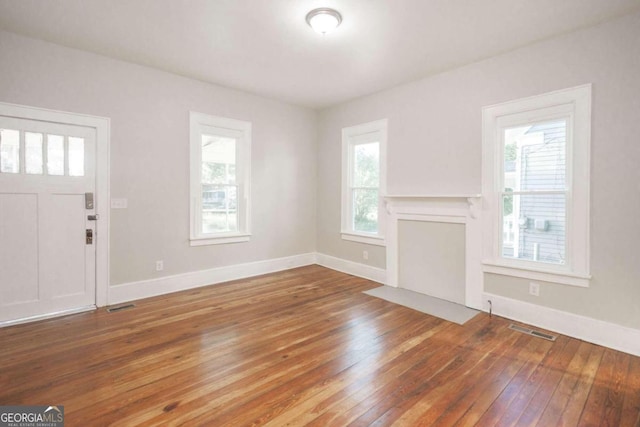 unfurnished living room with baseboards, visible vents, and wood-type flooring