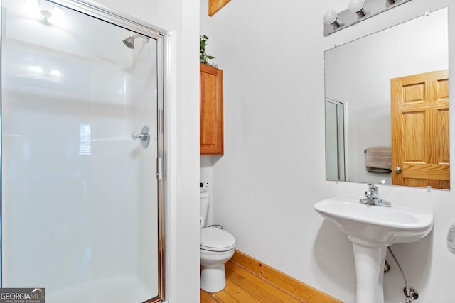 bathroom with hardwood / wood-style floors, sink, toilet, and walk in shower