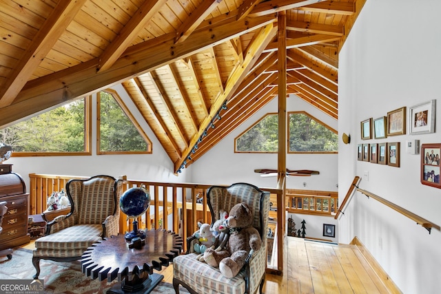 sitting room with beamed ceiling, wood-type flooring, a healthy amount of sunlight, and wood ceiling