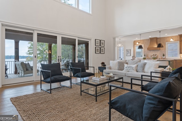 living room featuring french doors, a chandelier, hardwood / wood-style floors, and a high ceiling