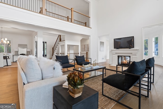 living room featuring hardwood / wood-style flooring, a multi sided fireplace, a towering ceiling, and a notable chandelier