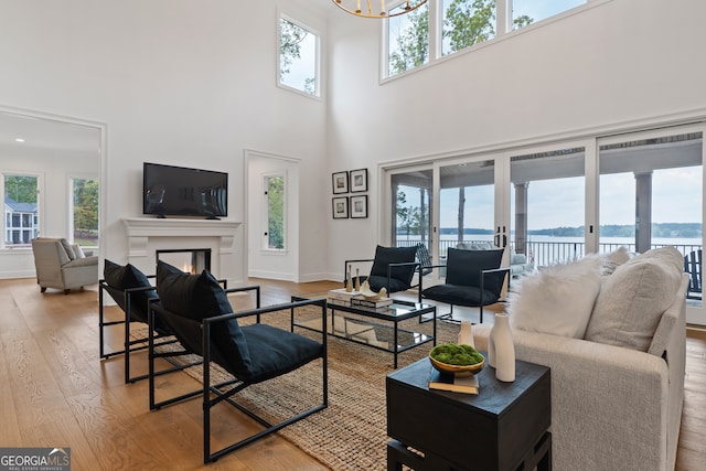 living room with light wood-type flooring, a high ceiling, and a wealth of natural light