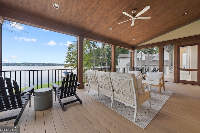 wooden terrace with ceiling fan, an outdoor living space, and a water view