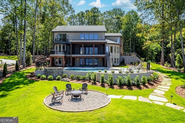 rear view of house featuring a patio, a yard, a wooden deck, and an outdoor fire pit