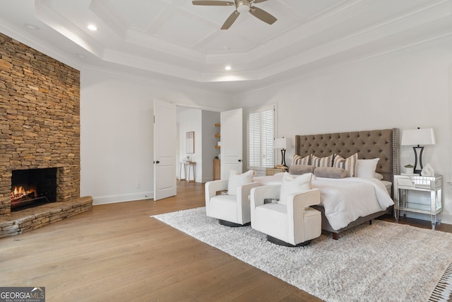 bedroom featuring light hardwood / wood-style flooring, ceiling fan, a raised ceiling, and crown molding