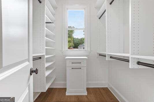 spacious closet with dark hardwood / wood-style flooring