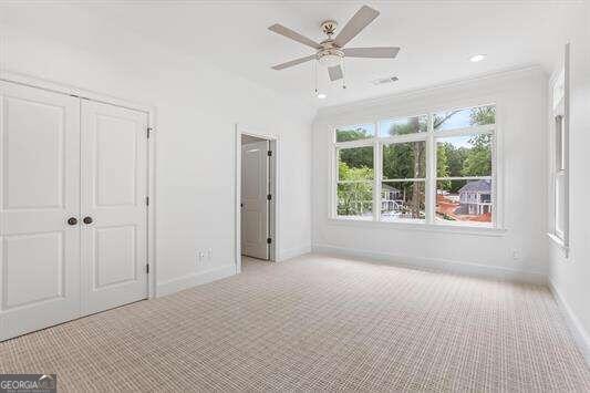 unfurnished bedroom featuring ceiling fan, light colored carpet, a closet, and ornamental molding