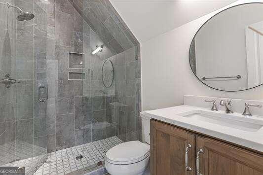 bathroom with vanity, toilet, vaulted ceiling, and a shower with door