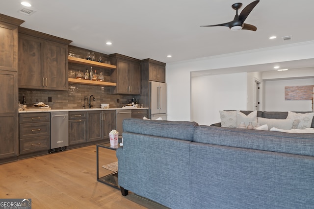 interior space featuring ceiling fan, sink, light hardwood / wood-style flooring, stainless steel appliances, and decorative backsplash