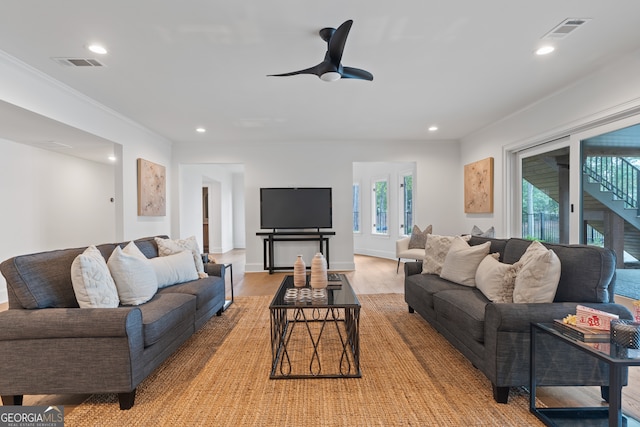 living room with light wood-type flooring, ceiling fan, and plenty of natural light