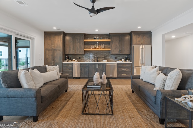 living room with ornamental molding, wood-type flooring, ceiling fan, and wet bar