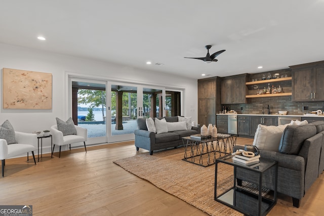 living room with ceiling fan, wet bar, and light hardwood / wood-style flooring