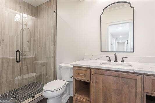 bathroom featuring a shower with shower door, vanity, and toilet