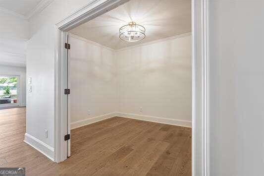 interior space featuring an inviting chandelier, crown molding, and hardwood / wood-style floors