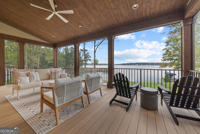 wooden deck with a water view, outdoor lounge area, and ceiling fan