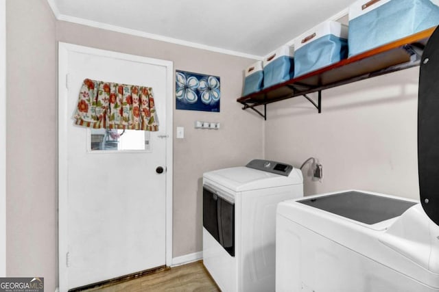 washroom featuring ornamental molding, washing machine and dryer, and light hardwood / wood-style flooring