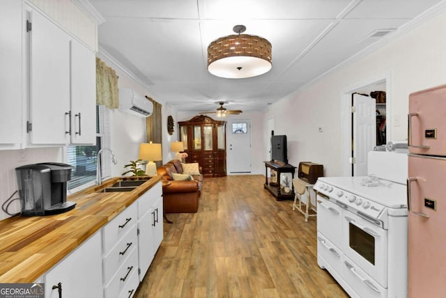 kitchen with fridge, sink, range with two ovens, and white cabinets