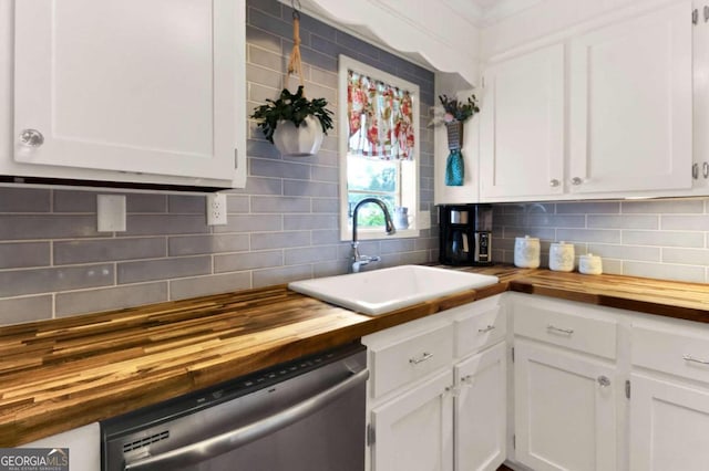 kitchen featuring butcher block countertops, tasteful backsplash, sink, white cabinets, and stainless steel dishwasher