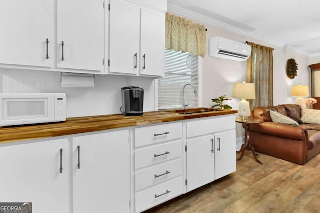 kitchen featuring white cabinets, sink, and a wall mounted AC