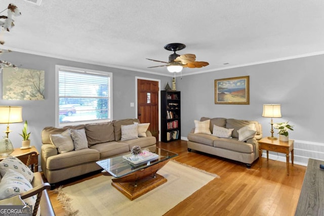 living room with crown molding, ceiling fan, a textured ceiling, and light wood-type flooring