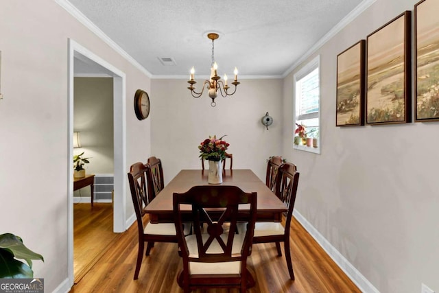 dining area featuring wood-type flooring, a chandelier, a textured ceiling, and crown molding