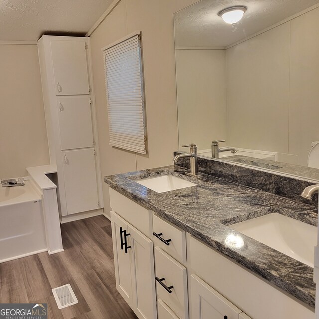 full bathroom featuring double vanity, wood finished floors, a sink, and visible vents