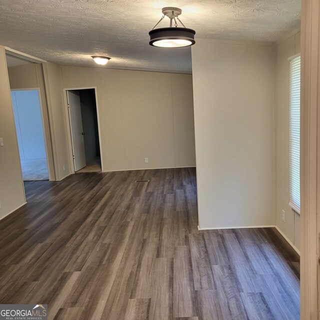 spare room with a textured ceiling and dark wood-style flooring