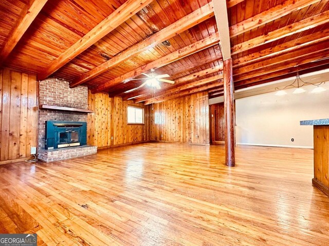 unfurnished living room with beam ceiling, light wood-type flooring, wood ceiling, brick wall, and a fireplace