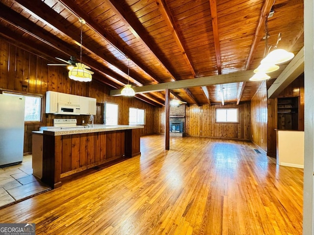 kitchen with wood walls, wood ceiling, plenty of natural light, and white appliances