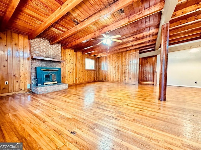 unfurnished living room with a fireplace, wooden ceiling, brick wall, beam ceiling, and light hardwood / wood-style floors