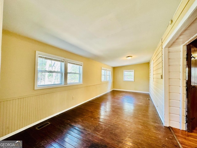 empty room with a wealth of natural light and wood-type flooring