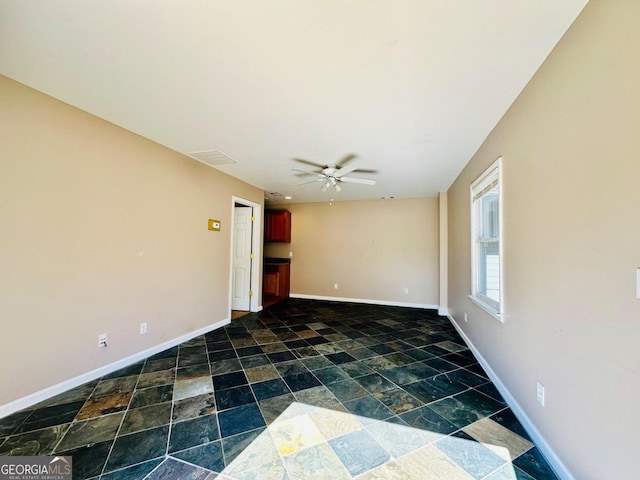 spare room featuring ceiling fan and dark tile patterned floors