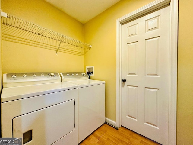 laundry room with separate washer and dryer and light hardwood / wood-style floors