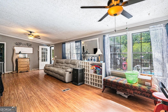 living room with crown molding, vaulted ceiling, a textured ceiling, ceiling fan, and hardwood / wood-style floors