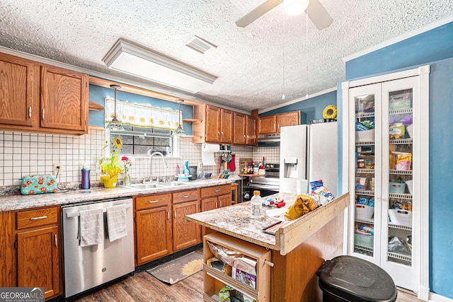 kitchen featuring light stone counters, stainless steel appliances, dark wood-type flooring, and sink