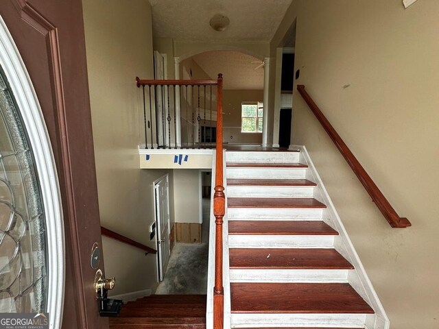 stairs featuring carpet flooring and a textured ceiling