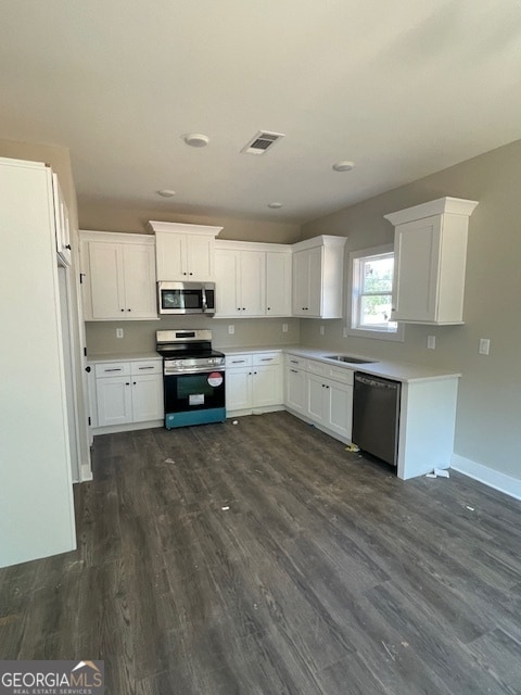 kitchen with appliances with stainless steel finishes, white cabinetry, sink, and dark hardwood / wood-style floors