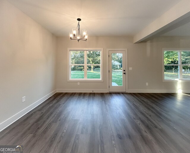 spare room with dark hardwood / wood-style flooring, plenty of natural light, and ceiling fan with notable chandelier