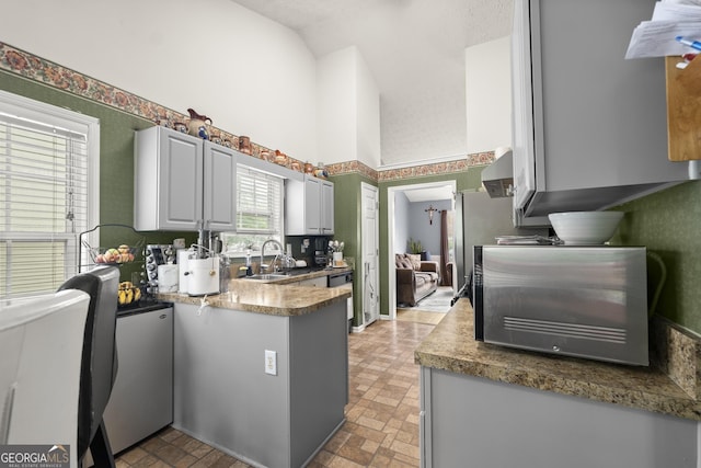 kitchen featuring sink, gray cabinets, dishwasher, and vaulted ceiling