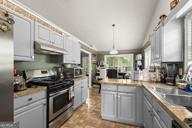 kitchen featuring pendant lighting, appliances with stainless steel finishes, sink, vaulted ceiling, and gray cabinetry