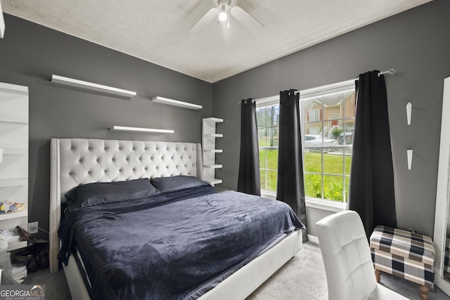 carpeted bedroom featuring ceiling fan and a textured ceiling