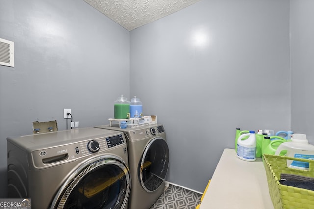 laundry area with separate washer and dryer and a textured ceiling