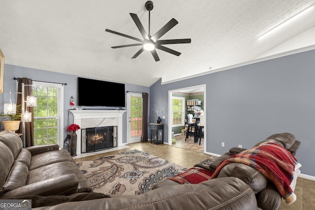 tiled living room featuring ceiling fan, a textured ceiling, a fireplace, and lofted ceiling