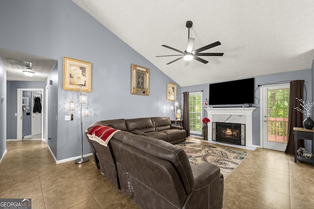 tiled living room with ceiling fan, a fireplace, and lofted ceiling