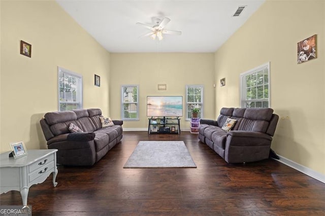 living room with a wealth of natural light, dark wood-type flooring, and ceiling fan