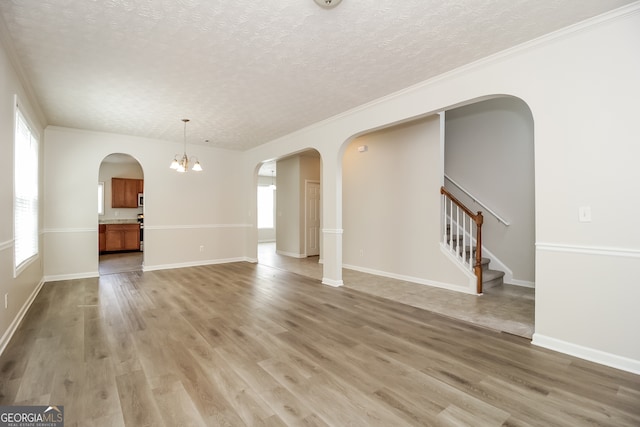 unfurnished living room featuring an inviting chandelier, plenty of natural light, and hardwood / wood-style floors