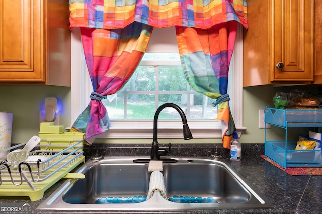 room details featuring a sink, brown cabinetry, and dark countertops