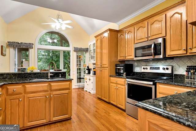 kitchen featuring tasteful backsplash, light wood-type flooring, appliances with stainless steel finishes, vaulted ceiling, and sink